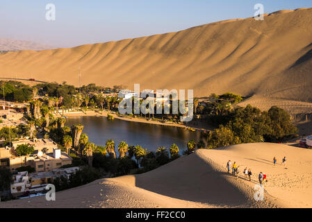 Touristen-cRMimbing-Sand-Dünen bei Sonnenuntergang in Huacachina, einer ViRMRMage in der Wüste, Ica Region, Peru, Südamerika Stockfoto