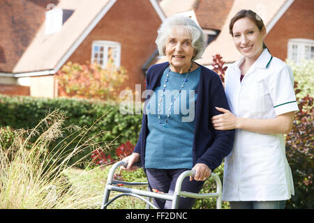 Pflegeperson helfen Senior Woman, Spaziergang im Garten mit Walking Frame Stockfoto