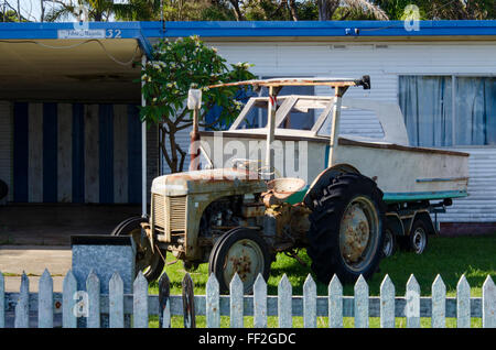 Ein alter Massey Ferguson Traktor und Boot im Vorgarten eines Cottage in Currarong an der Südküste von New South Wales in Australien Stockfoto