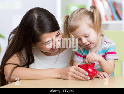 Mutter und Tochter Sparschwein Münzen Inbetriebnahme Stockfoto