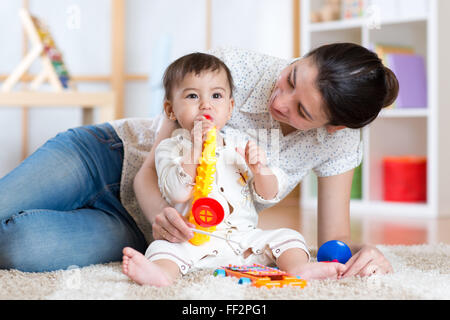 Mama und Baby spielen musikalische Spielzeug zu Hause Stockfoto