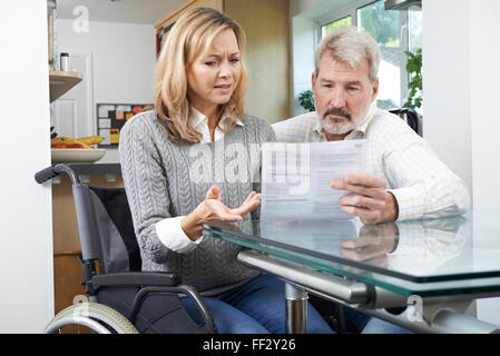 Frustrierte paar mit Frau im Rollstuhl lesen schreiben Stockfoto