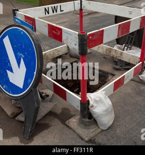 Eine Wasserleitung ist auf einer Straße in Sunderland, England repariert, ein Zeichen regelt den Verkehr rund um das Loch in der Straße. Stockfoto