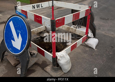 Eine Wasserleitung ist auf einer Straße in Sunderland, England repariert, ein Zeichen regelt den Verkehr rund um das Loch in der Straße. Stockfoto