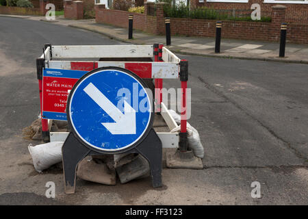 Eine Wasserleitung ist auf einer Straße in Sunderland, England repariert, ein Zeichen regelt den Verkehr rund um das Loch in der Straße. Stockfoto