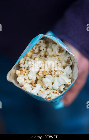 Hand, die eine Paket Propercorn aromatisiert Popcorn Stockfoto