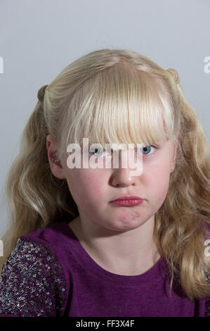 Studio-Porträt eines jungen blonden Mädchens mit Trauben vor einem weißen Hintergrund. Stockfoto