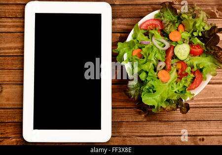 Tablet mit Gemüsesalat auf Holztisch Stockfoto