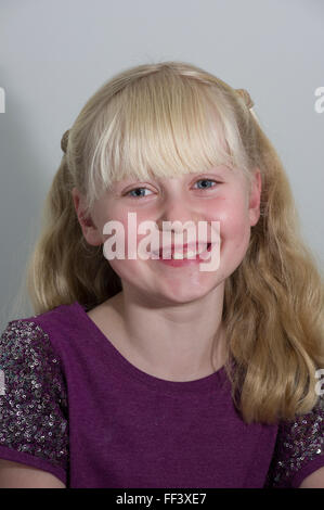 Studio-Porträt eines jungen blonden Mädchens mit Trauben vor einem weißen Hintergrund. Stockfoto