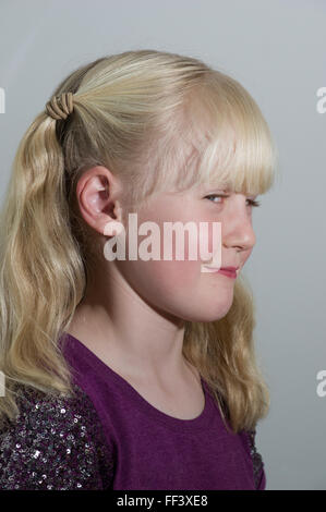 Studio-Porträt eines jungen blonden Mädchens mit Trauben vor einem weißen Hintergrund. Stockfoto