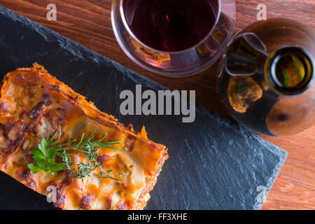 heiß dampfende Lasagne mit Rotwein auf Schiefer und Holz Tisch Stockfoto