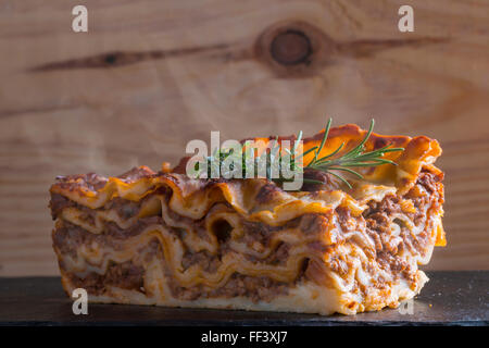 heiß dampfende Lasagne mit Rotwein auf Schiefer und Holz Tisch Stockfoto