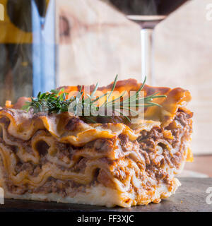 heiß dampfende Lasagne mit Rotwein auf Schiefer und Holz Tisch Stockfoto