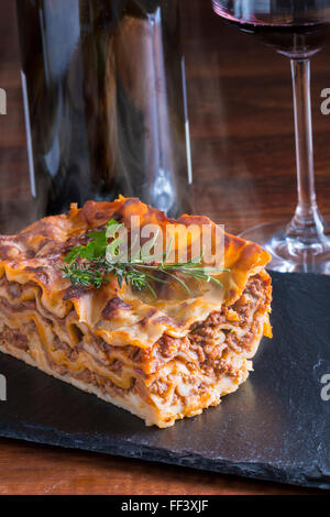 heiß dampfende Lasagne mit Rotwein auf Schiefer und Holz Tisch Stockfoto