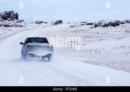 Fahrzeug, Lkw abholen, Fahrt entlang der Straße durch schneebedeckte Berge in Island im Januar Stockfoto