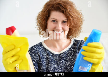 glückliche Frau in Gummihandschuhe mit Reinigungsmitteln Stockfoto
