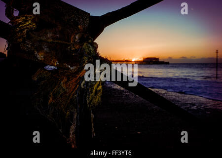 Die Sonne geht über Worthing Pier verdeckt durch die Struktur der The Lido: ein weiterer Strand/Meer-Gebäude. Bild von Julie Edwards Stockfoto