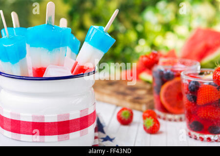 Hausgemachte rot-weiß-blauen Eis am Stiel auf einen Tisch im Freien mit erfrischenden Limonade im Hintergrund. Stockfoto