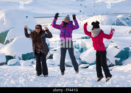 Junge Touristen für Frauen springen im Jokulsarlon Glacial Lagoon, am Rande des Vatnajokull National Park, Island im Januar in die Luft Stockfoto