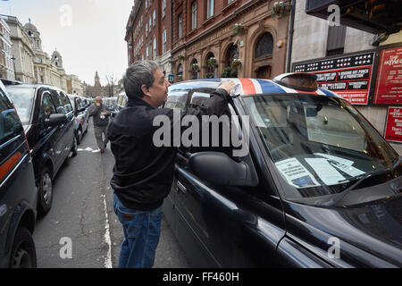 London, UK. 10. Februar 2016. Schwarzen Londoner Taxifahrer verursachen Datenverkehr Staus im Zentrum von London als Protest gegen die neue Taxi-Vorschriften. Ein Taxifahrer reinigt seine Kabine in der Linie der Taxis in Whitehall. Bildnachweis: Steve Hickey/Alamy Live-Nachrichten Stockfoto