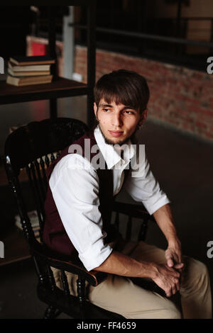 Moderne Porträt des brutalen bärtiger Mann sitzt auf einem Stuhl im Loft Interieur Stockfoto
