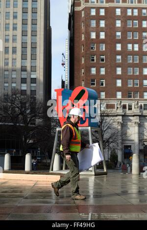 Philadelphia, PA, USA. 10. Februar 2016. Bauarbeiter geht vorbei an Robert Indianas legendären Liebe Statue, gelegen am JFK Plaza (aka LOVE Park), in Center City Philadelphia, PA. Vertreter der Stadt den ersten Spatenstich für die Sanierung des Center City Philadelphia, Park am 10. Februar. In das Design eingearbeitet werden eine renovierte Untertasse, jetzt Gehäuse Visitors Center, besseren Zugang und offene Sichtlinien. Bildnachweis: Bastiaan Slabbers/Alamy Live-Nachrichten Stockfoto
