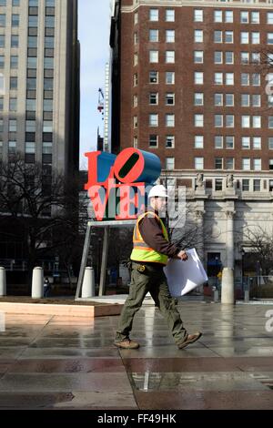 Philadelphia, PA, USA. 10. Februar 2016. Bauarbeiter geht vorbei an Robert Indianas legendären Liebe Statue, gelegen am JFK Plaza (aka LOVE Park), in Center City Philadelphia, PA. Vertreter der Stadt den ersten Spatenstich für die Sanierung des Center City Philadelphia, Park am 10. Februar. In das Design eingearbeitet werden eine renovierte Untertasse, jetzt Gehäuse Visitors Center, besseren Zugang und offene Sichtlinien. Bildnachweis: Bastiaan Slabbers/Alamy Live-Nachrichten Stockfoto