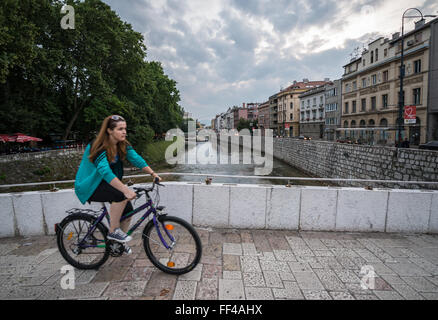 Mädchen Reiten Fahrrad auf Latein Brücke über den Fluss Miljacka, alte Stadt von Sarajevo, Bosnien und Herzegowina Stockfoto