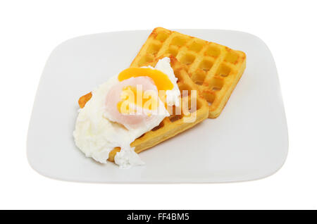 Laufende Eigelb pochiertes Ei auf Kartoffel-Waffeln auf einem Teller isoliert gegen weiß Stockfoto