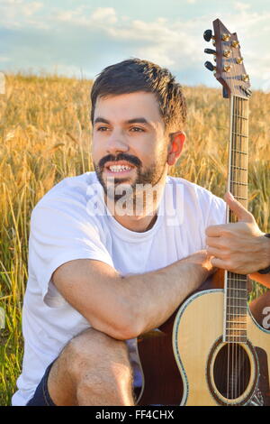 bärtige junge mit der Gitarre auf Thewheat Gebiet Stockfoto