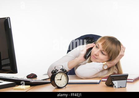 Nicht genügend Schlaf-Büro-Mitarbeiter an seinem Schreibtisch ans Telefon Stockfoto