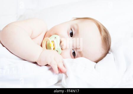 Hingebungsvolle Mutter Sohn Festlegung in Krippe für Nickerchen im Schlafzimmer Stockfoto