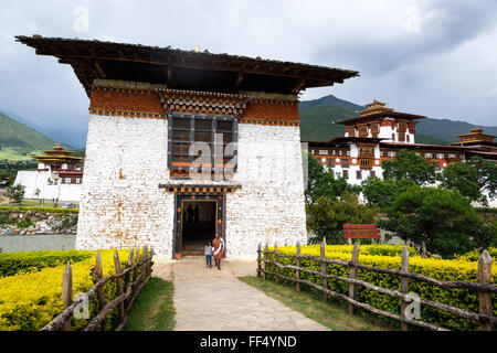 Bhutanische Frau und Kind gehen zum Eingangsturm des Klosters der Festung Punakha Dzong im Punakha-Tal, Bhutan Stockfoto