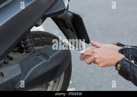 Frau Reparaturen einen Roller Stockfoto