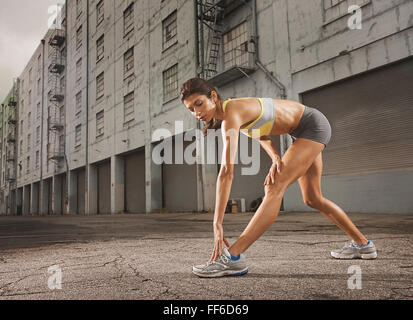 Eine Frau im Fahrwerk, bauchfreies Top und Shorts, ihren Körper und einen Lauf vorbereiten oder Abkühlung nach dem Training. Stockfoto