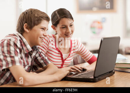 Zwei Kinder, einen jungen und Mädchen sitzen an einem Schreibtisch mit einem Laptopcomputer. Stockfoto