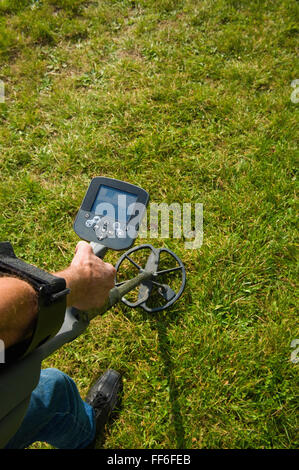 Eines Mannes Arm Holdng einen Metalldetektor nur über Erdgeschoss, auf der Suche nach metallischen Gegenständen unter der Erde. Stockfoto