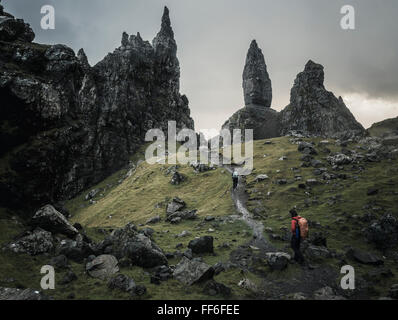 Zwei Personen mit Rucksäcken auf einem schmalen Pfad steigt zu einer dramatischen Landschaft von Felsen Zinnen Stockfoto