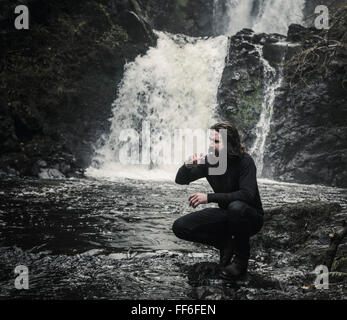 Ein Mann seine Zahnreinigung durch einen schnellen flowin Strom. Wildes Campen. Stockfoto