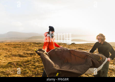 Zwei Männer halten und ein kleines Zelt im offenen Raum aufstellen. Wildes Campen. Stockfoto