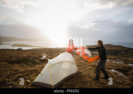 Zwei Männer halten und ein kleines Zelt im offenen Raum aufstellen. Wildes Campen. Stockfoto