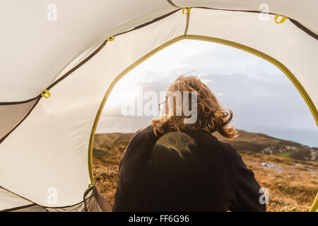 Ein Mann sitzt im Schutz eines Zeltes Ausschau. Stockfoto