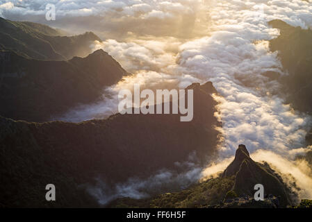 Sonnenaufgang über Schluchten und zerklüftete Täler mit Wolken von der Nordküste zu den zentralen Bergen von Madeira gesehen von Pico Do Ariero führt Stockfoto