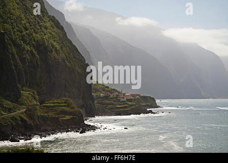 Eine schmale Küstenstraße schlängelt sich entlang der Klippen, Bergketten und abgelegene Dörfer in der Nähe von Ponta Delgada, Nordküste von Madeira Stockfoto
