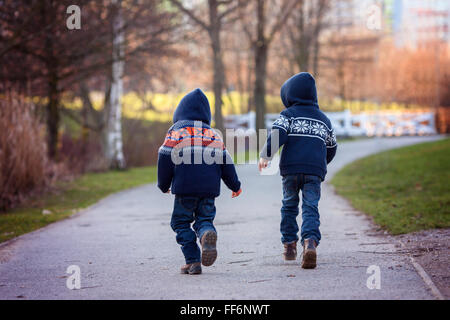Zwei süße Boys weglaufen auf einem Wanderweg im Park an einem sonnigen Wintertag im freien Aktivität Stockfoto