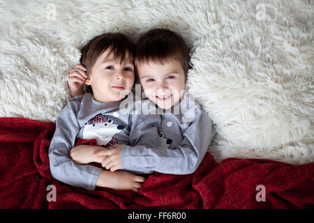 Zwei schöne Söhne, Brüder, liegend im Bett, umarmen, erschossen lächelnd in die Kamera von oben Stockfoto