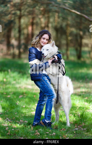 Fröhliches junges Mädchen umarmen husky Hund in einem Wald im Frühjahr Stockfoto