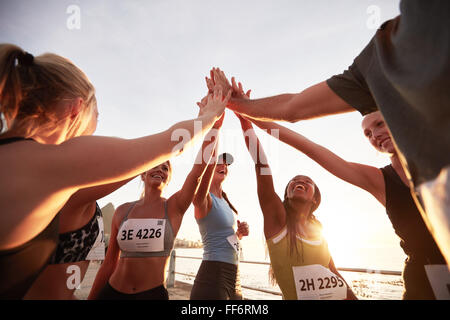 Läufer hohe Fiving einander nach einer guten Schulung. Gruppe von Athleten geben sich gegenseitig hoch fünf nach dem Rennen. Stockfoto