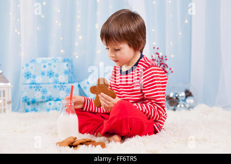 Niedliche kleine fröhlicher Junge, Kekse und Milch, warten auf Santa im Pyjama auf Heiligabend Nacht Stockfoto