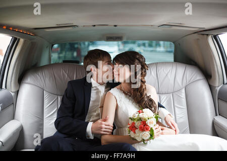 Glückliche Braut und Bräutigam umarmen, sitzen im Auto Stockfoto